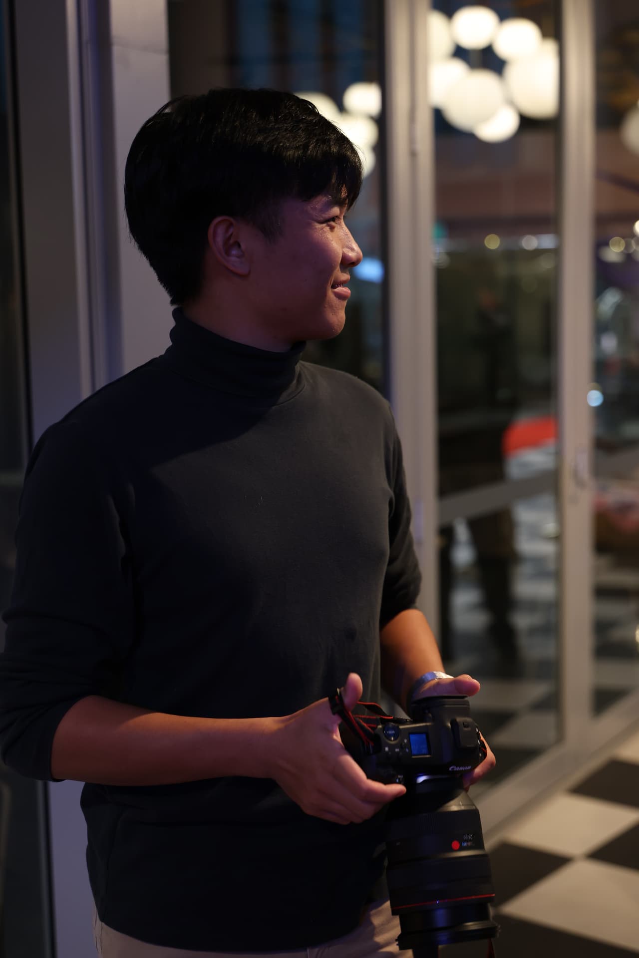 Harry Liu in profile at night holding a Canon camera