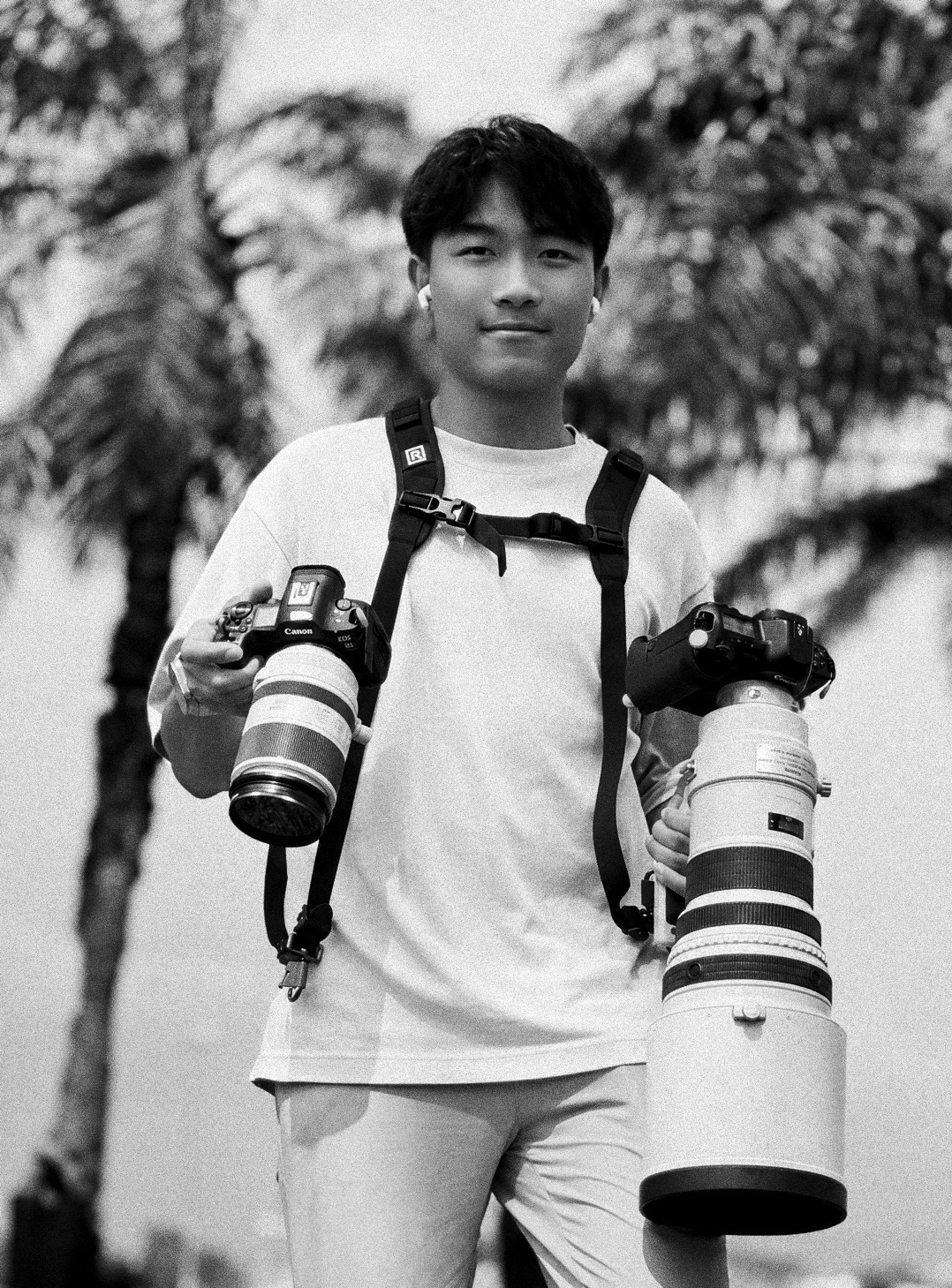 Black and white portrait of Harry Liu carrying two cameras on a harness